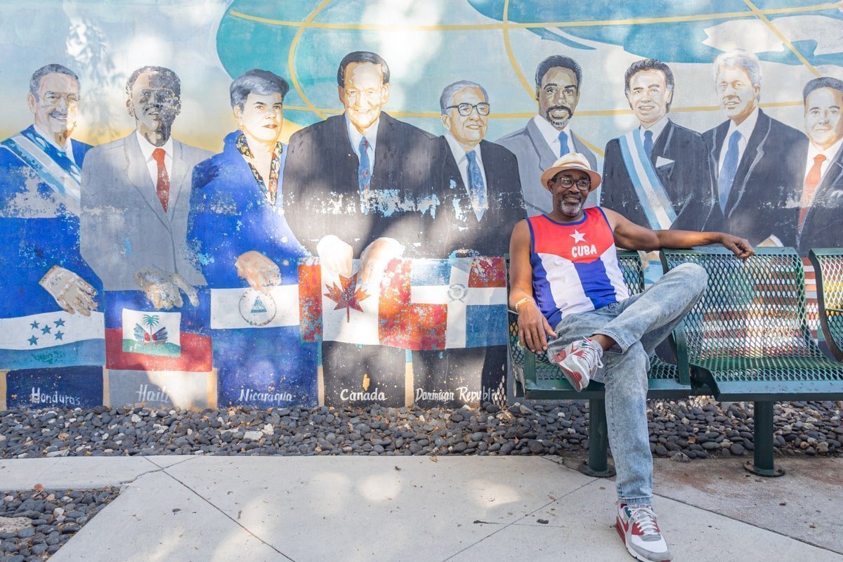 Un habitant avec un T-shirt représentant le drapeau cubain assis devant un street art