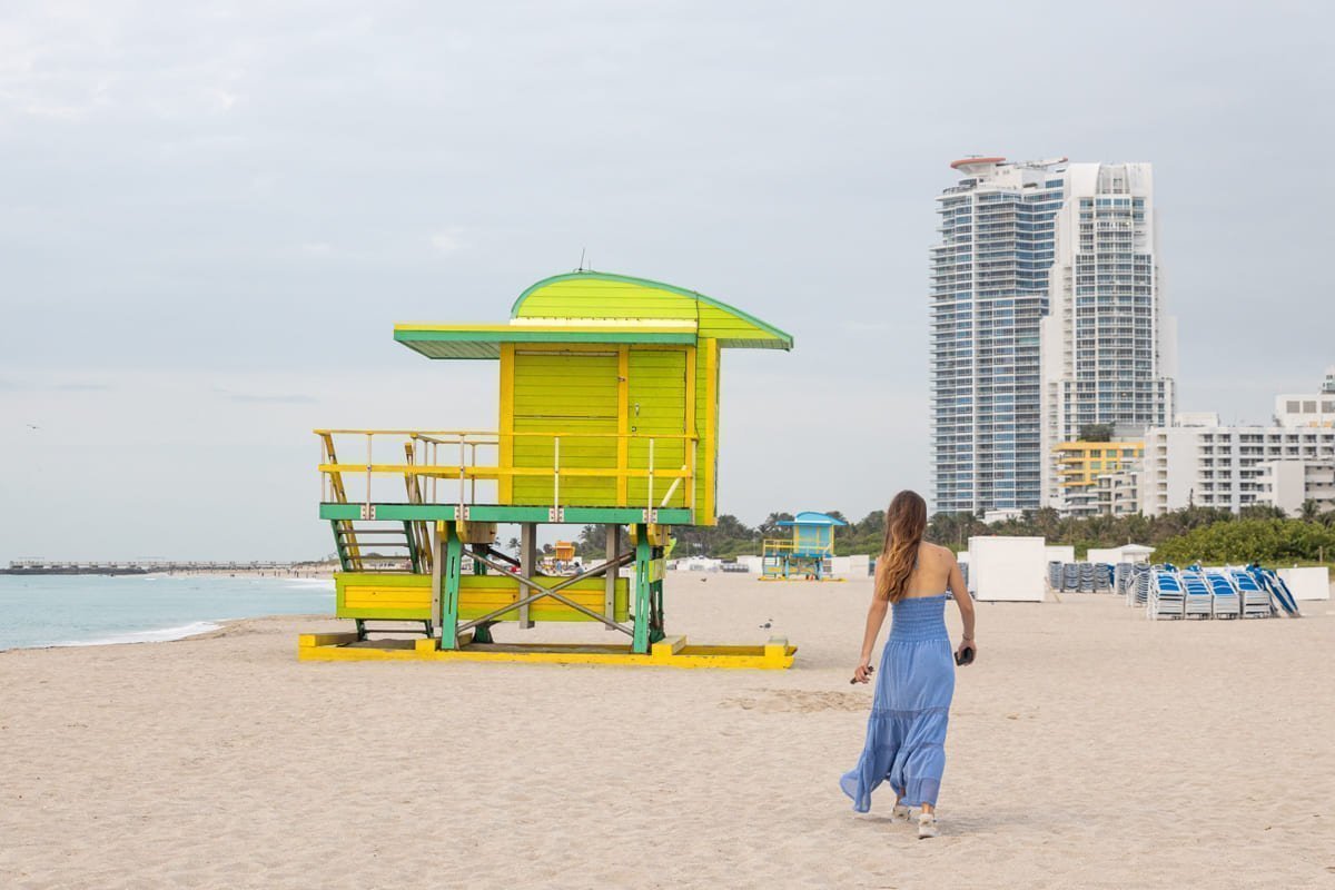Femme qui marche vers une cabane jaune sur la plage
