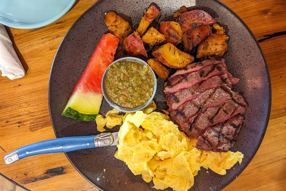 Assiette avec viande, pomme de terre, omelette, sauce et pastèque