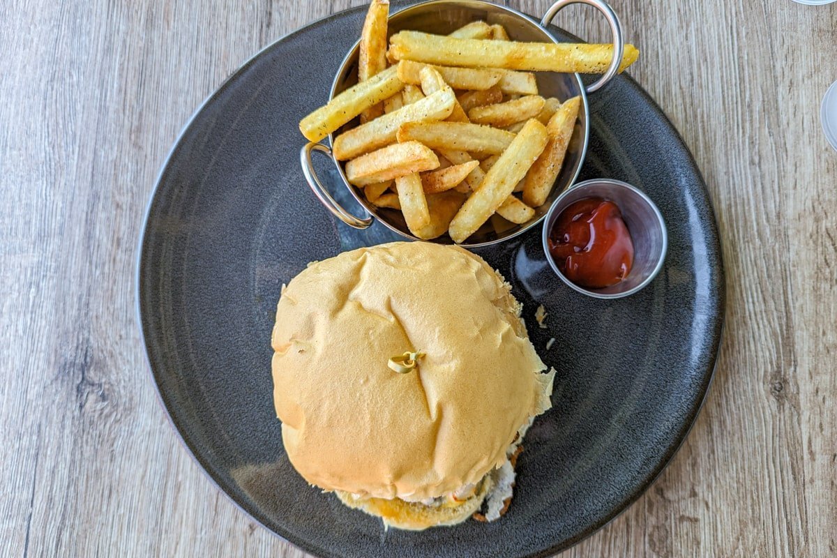 Burger dans une assiette avec des frites et une sauce
