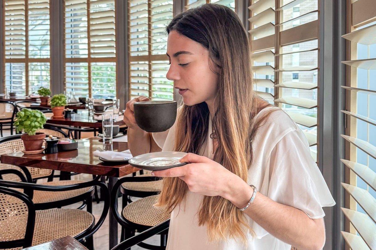 Femme à table qui tient une tasse de café