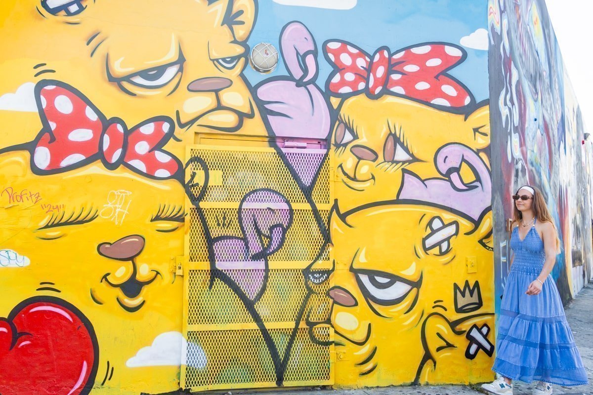 Une personne qui marche devant un graffiti avec des chats jaunes