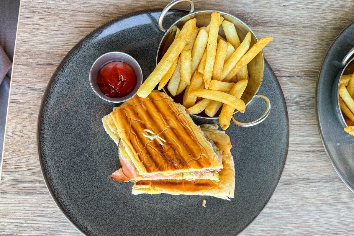 Sandwich sur une assiette avec des frites et une sauce